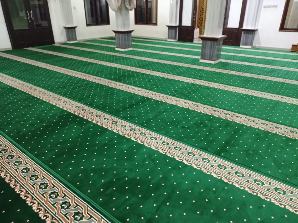 Karpet masjid hijau terpasang rapi di antara pilar
